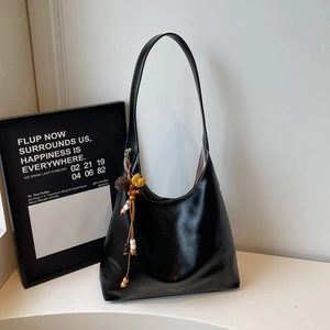 Detail of black hobo tote with contrast white stitching and ethnic beaded charm tassel