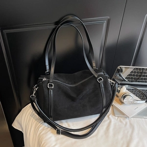 Detail of black suede Boston bag showing leather handles and textured matte finish