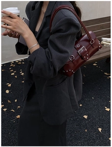 Detail of dark red vintage underarm bag with silver studs and buckles in autumn setting