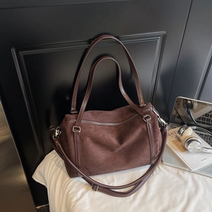 Detailed close-up of dark brown suede Boston bag with silver hardware and leather straps