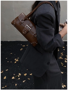 Detailed view of dark brown leather underarm bag with silver rivets and buckle