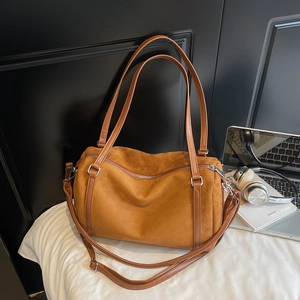 Close-up of brown suede Boston bag featuring silver hardware and durable double handles