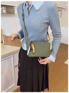 Detail of avocado green quilted crossbody bag with stylish multi-colored beaded pendant