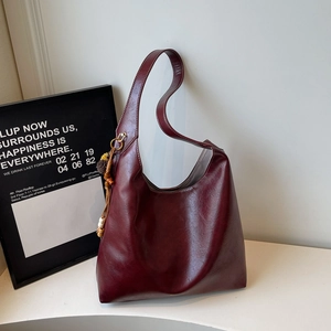 Detail of burgundy oversized tote bag in oily leather with bohemian wooden bead tassels