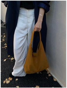 Détail du sac cabas en similicuir jaune moutarde mat avec une silhouette minimaliste élégante et arrondie