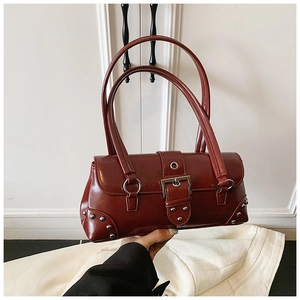 Detail shot of vintage burgundy glossy leather bag with metallic buckle and silver studs