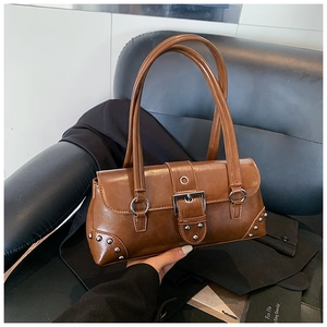 Detailed macro view of vintage brown PU leather texture and silver rivets on the shoulder bag