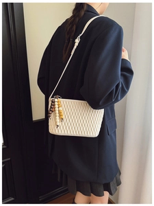 Detail of white quilted bucket bag with colorful wooden beads and leather strap