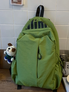 Green water-resistant nylon backpack for travel with cute dog plush toy pendant