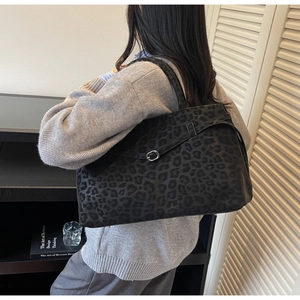 Detail of a large leopard print suede tote bag carried by a model in a casual setting