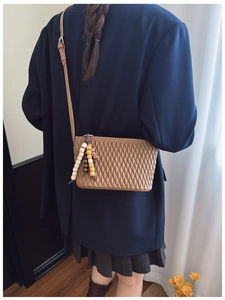 Detailed close-up of brown quilted crossbody bag featuring ethnic style beaded tassels