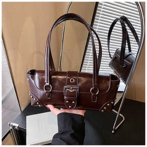 Detailed macro view of dark brown glossy leather bag with silver rivets and metal rings