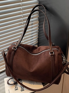 Retro coffee brown suede Boston bag with silver hardware and shoulder strap in soft window light
