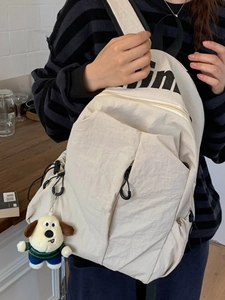 Large off-white nylon backpack with dog plush toy shown on a female model