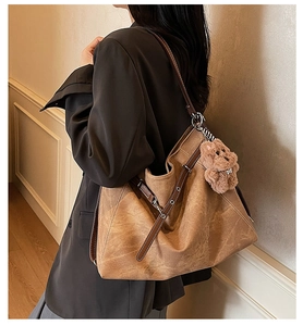 Detail of vintage brown tote bag with smooth texture and cute plush bear charm accessory