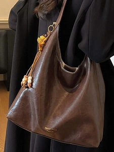 Large dark brown leather tote bag with tassel charm and wide shoulder strap