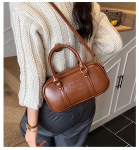 Brown leather cylindrical Boston bag with MIRA MIRA logo worn as a crossbody bag
