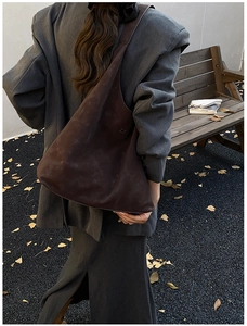 Détail du sac hobo en daim marron foncé porté à l'épaule dans un style d'automne chic