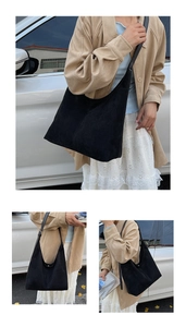 Detail view of large black matte suede tote bag worn over shoulder with elegant outfit