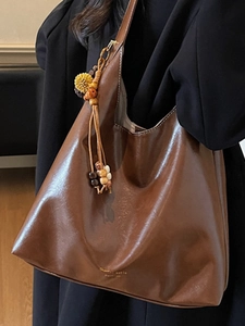 Brown minimalist hobo tote bag with beaded tassel charm and golden logo detail