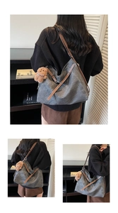 Detail view of large grey canvas hobo bag with brown leather strap and plush bear charm