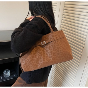 Detail view of large brown leopard print suede tote bag with metal buckle and strap decoration