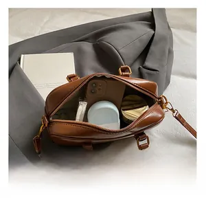 Detailed interior view of a brown leather Boston bag showing phone and cosmetics space