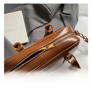 Detail of premium golden metal zipper and brown leather texture on a retro boston bag