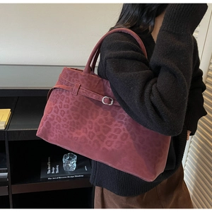 Detail der burgunderfarbenen Handtasche mit Leopardenmuster und Metallschnalle