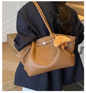 Detail view of lychee pattern leather shoulder bag in dark brown with plush pendant charm