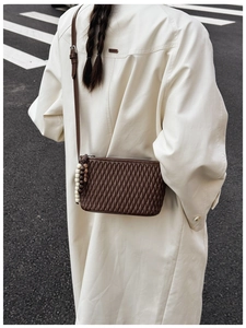 Detailed view of dark brown quilted crossbody bag with unique wooden bead accessory charm