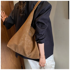 Gros plan du sac en cuir mat marron avec logo doré sur un blazer à rayures