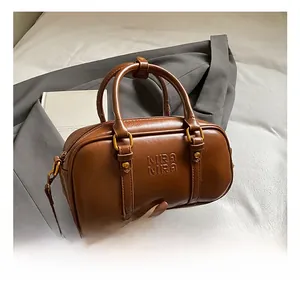 Detailed view of brown retro Boston bag with embossed logo and bronze hardware finish