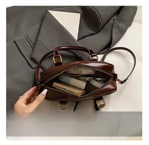 Vue détaillée du sac Boston marron chocolat montrant l'intérieur spacieux et la boucle dorée
