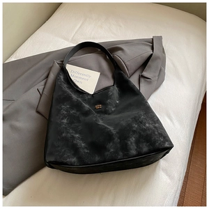 Détail du sac Hobo noir montrant le tissu synthétique texturé et le logo doré