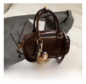 Détail du sac Boston marron foncé avec logo Mira Mira et charmant pendentif petit ours