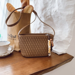 Detail of dark brown crossbody bag with diamond quilting and wooden bead charm