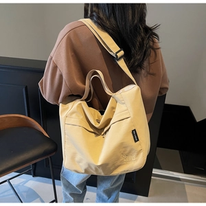 Detail view of beige canvas tote bag featuring embroidered dog and wide shoulder strap