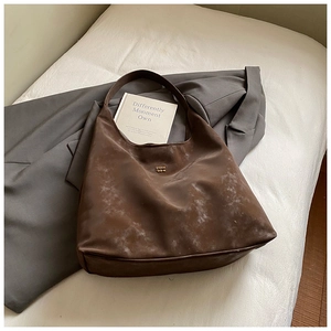 Vue détaillée du sac hobo marron foncé avec texture givrée vintage et logo doré
