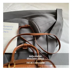Detail showing the adjustable long leather shoulder strap and vintage metal hardware on the bag