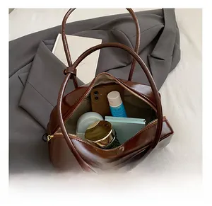 Internal capacity of the brown PU leather bowling bag with daily essentials inside