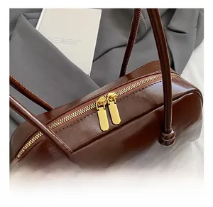 Detailed close-up of premium gold-tone dual zippers on a dark brown leather handbag