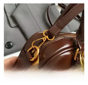 Détail des crochets dorés et de la texture en similicuir marron sur le sac à main chic