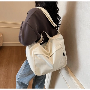 Detailed macro view of cream canvas tote bag with adjustable strap and side brand label