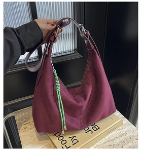 Detail of burgundy suede hobo bag with braided tassel and silver buckle handle