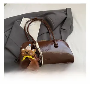 Close-up of vintage dark brown leather bowling bag with cute teddy bear charm