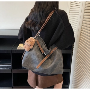 Deep gray canvas tote bag detail featuring brown leather straps and cute plush bear charm