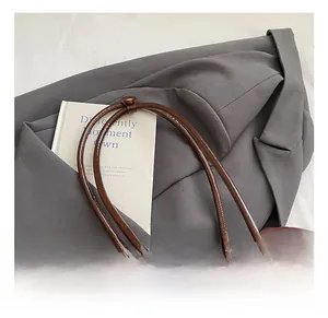 Detailed close-up of glossy dark brown leather bowling bag with slim rounded handles