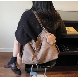 Macro detail of a large vintage brown tote bag with a cute plush bear charm on a model