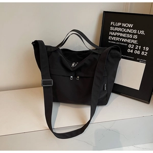 Detail of waterproof black nylon tote bag with front dual zipper pockets on marble surface